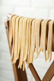 Homemade pasta drying on chair against white background, closeup