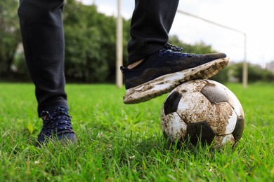 Photo of Man with dirty soccer ball on green grass outdoors, closeup