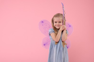 Photo of Cute little girl in fairy costume with violet wings and magic wand on pink background, space for text