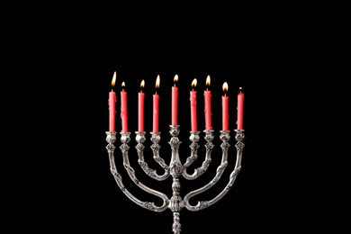 Photo of Silver menorah with burning candles against black background. Hanukkah celebration