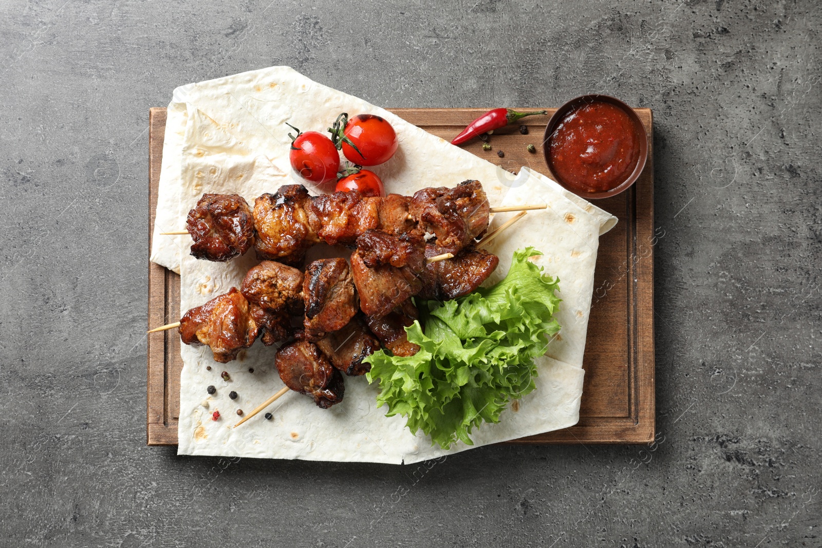 Photo of Delicious juicy meat served for barbecue party on gray table, top view