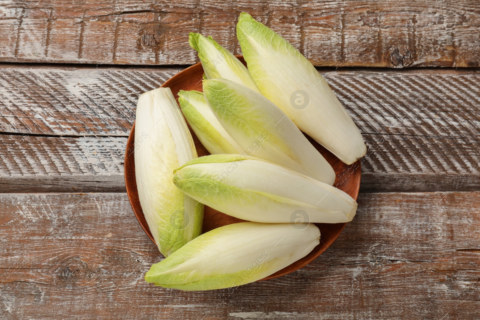 Photo of Fresh raw Belgian endives (chicory) on wooden table, top view