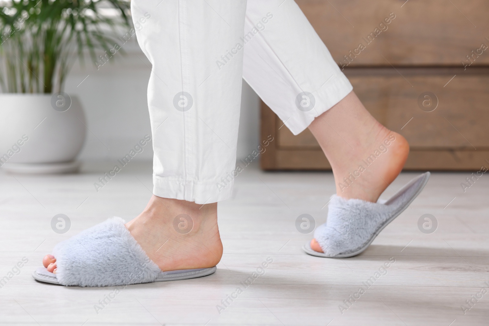 Photo of Woman in grey soft slippers at home, closeup