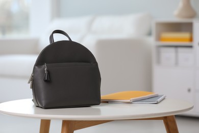 Stylish black backpack and notebooks on white table indoors, space for text