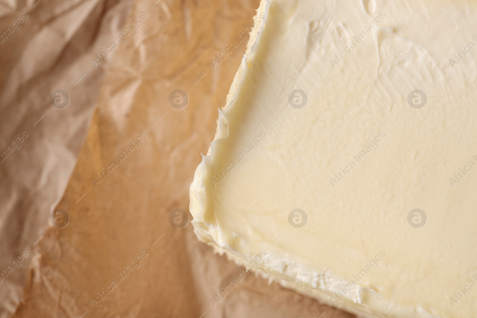 Photo of Piece of tasty homemade butter on parchment, closeup. Space for text