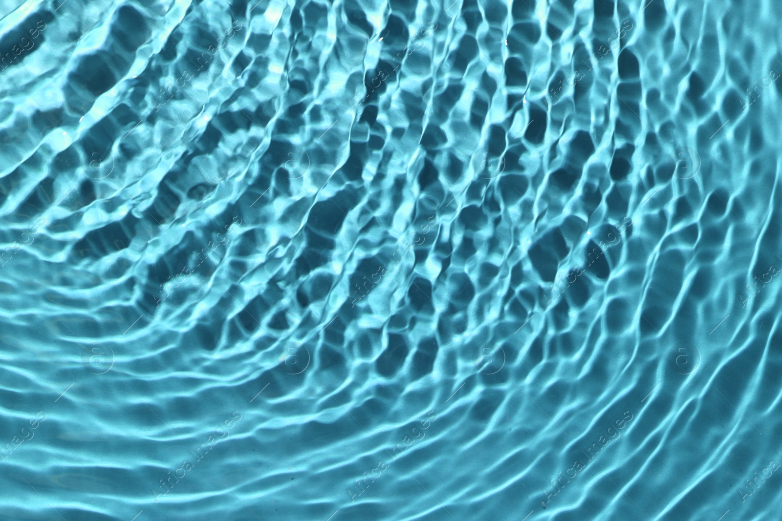 Image of Rippled surface of clear water on light blue background, closeup