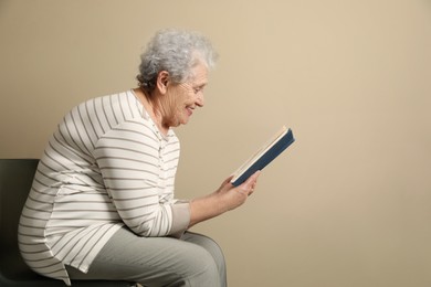 Elderly woman with poor posture reading book on beige background