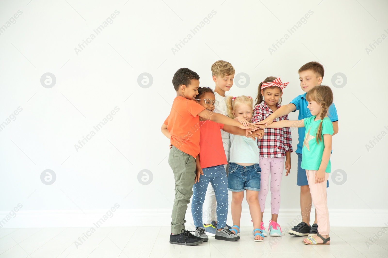 Photo of Little children putting their hands together on light background. Unity concept