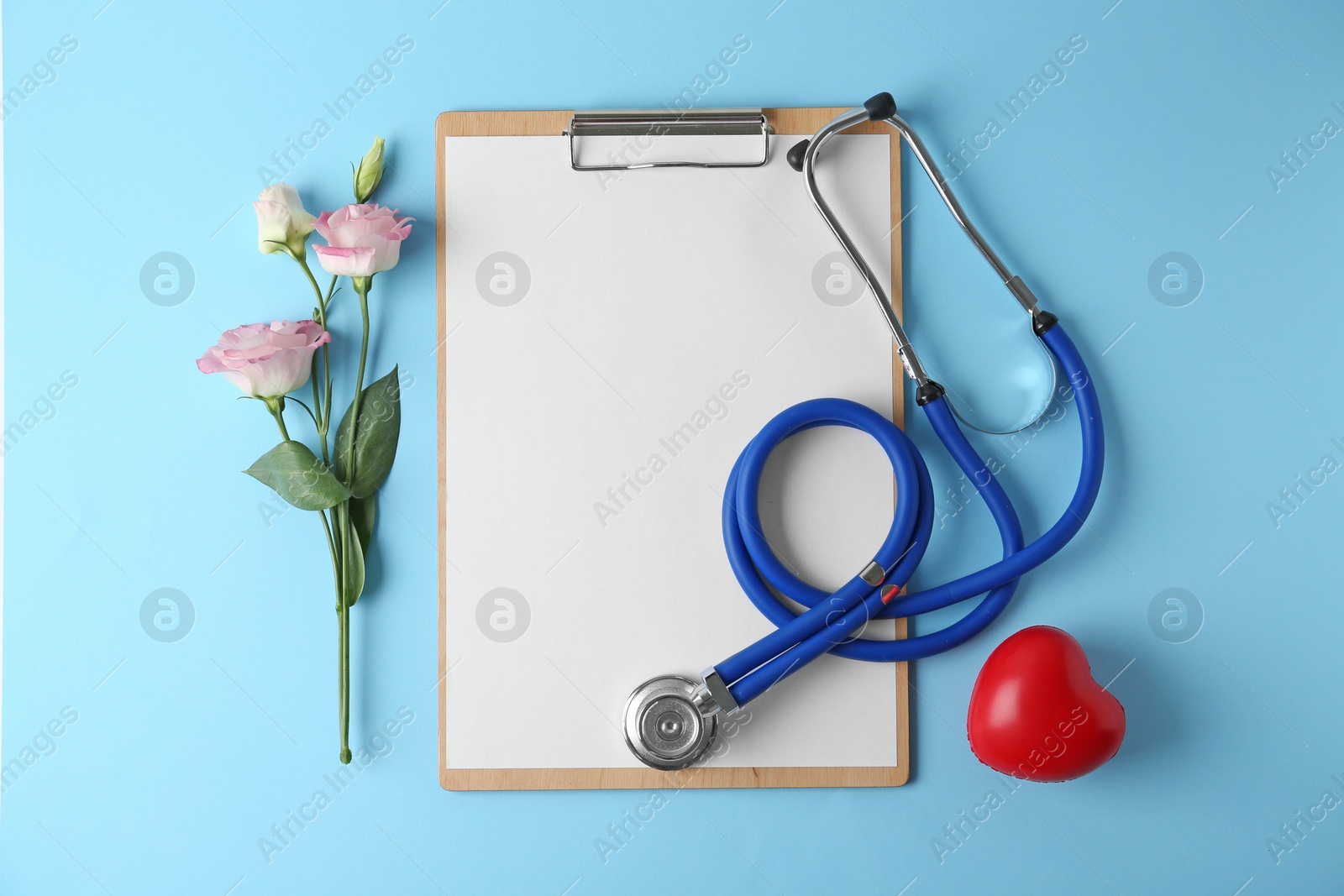 Photo of Flat lay composition with stethoscope and flowers on light blue background, space for text. World health day