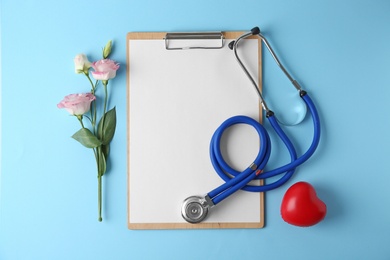 Photo of Flat lay composition with stethoscope and flowers on light blue background, space for text. World health day