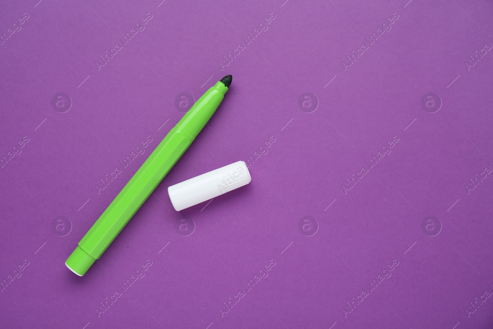Photo of Light green marker on purple background, flat lay. Space for text