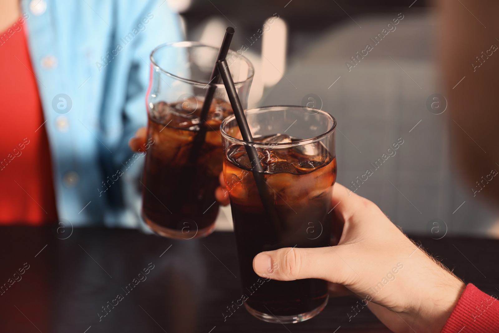 Photo of Young couple with glasses of cola at table indoors, closeup