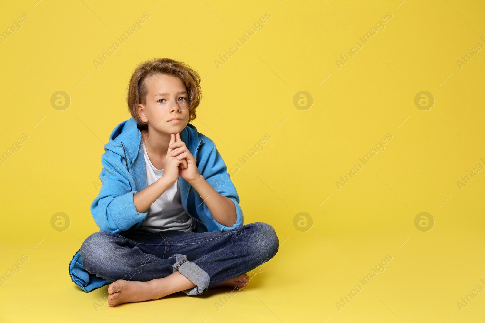 Photo of Cute little boy in casual outfit on yellow background. Space for text