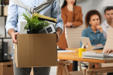 Photo of Upset dismissed man carrying box with stuff in office, closeup