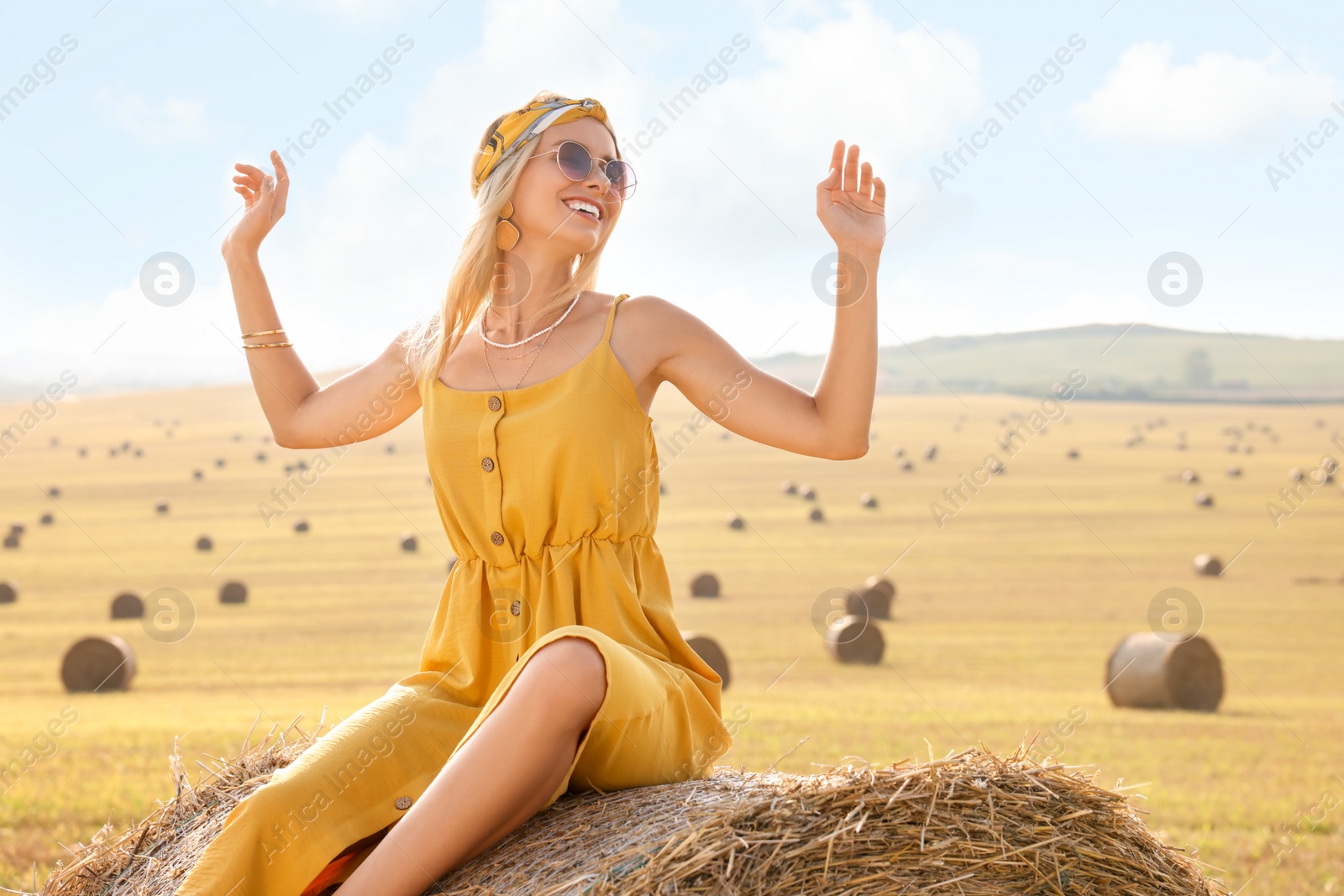 Photo of Beautiful hippie woman on hay bale in field, space for text