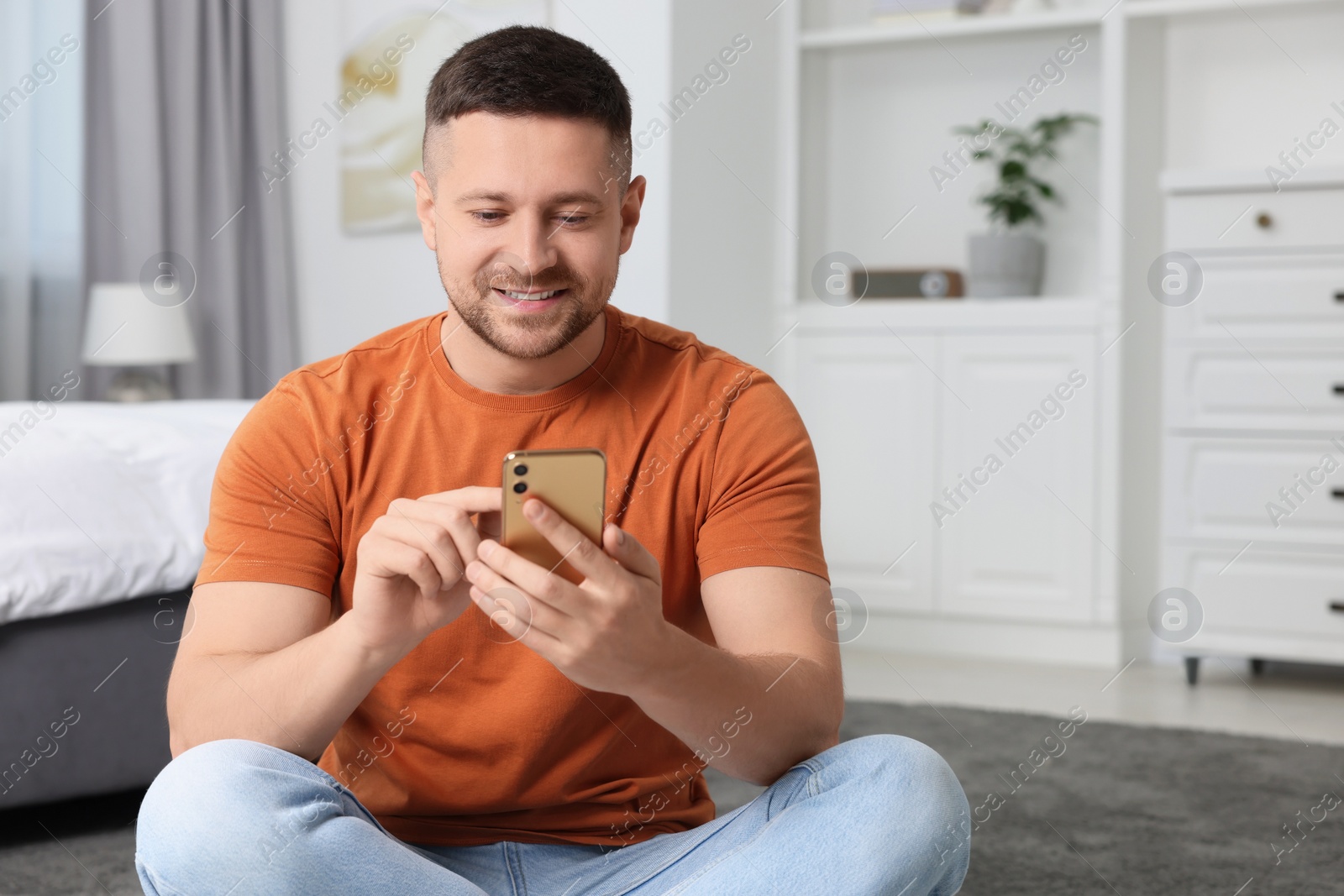 Photo of Handsome man sending message via smartphone at home. Space for text