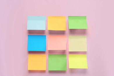 Blank colorful sticky notes on pink background, flat lay