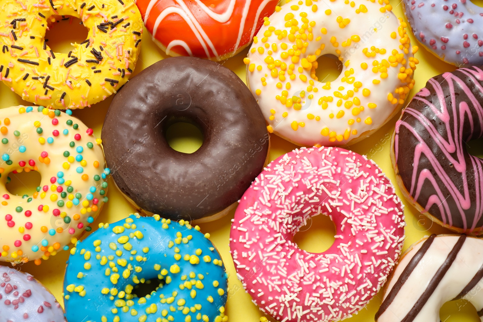 Photo of Delicious glazed donuts on yellow background, flat lay