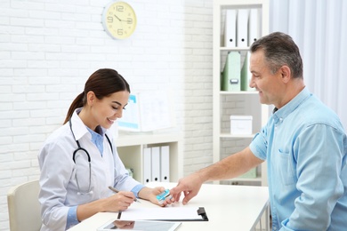 Photo of Doctor checking mature man's pulse with medical device in hospital