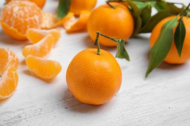 Fresh ripe tangerines with green leaves on table