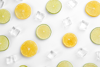 Lemonade layout with ice cubes, lime and orange slices on white background, top view