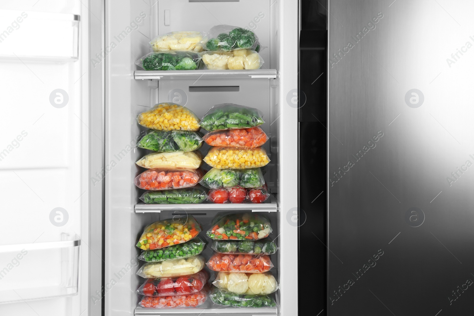 Photo of Plastic bags with different frozen vegetables in refrigerator