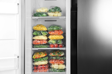 Plastic bags with different frozen vegetables in refrigerator