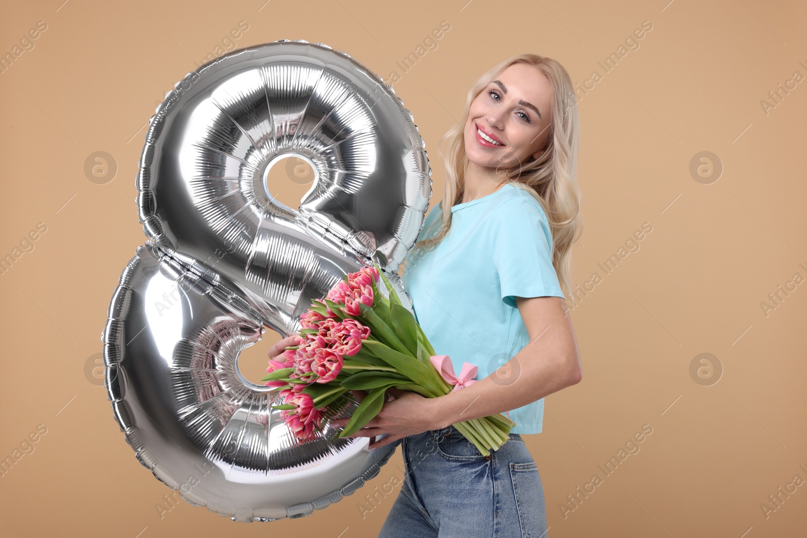 Photo of Happy Women's Day. Charming lady holding bouquet of beautiful flowers and balloon in shape of number 8 on beige background