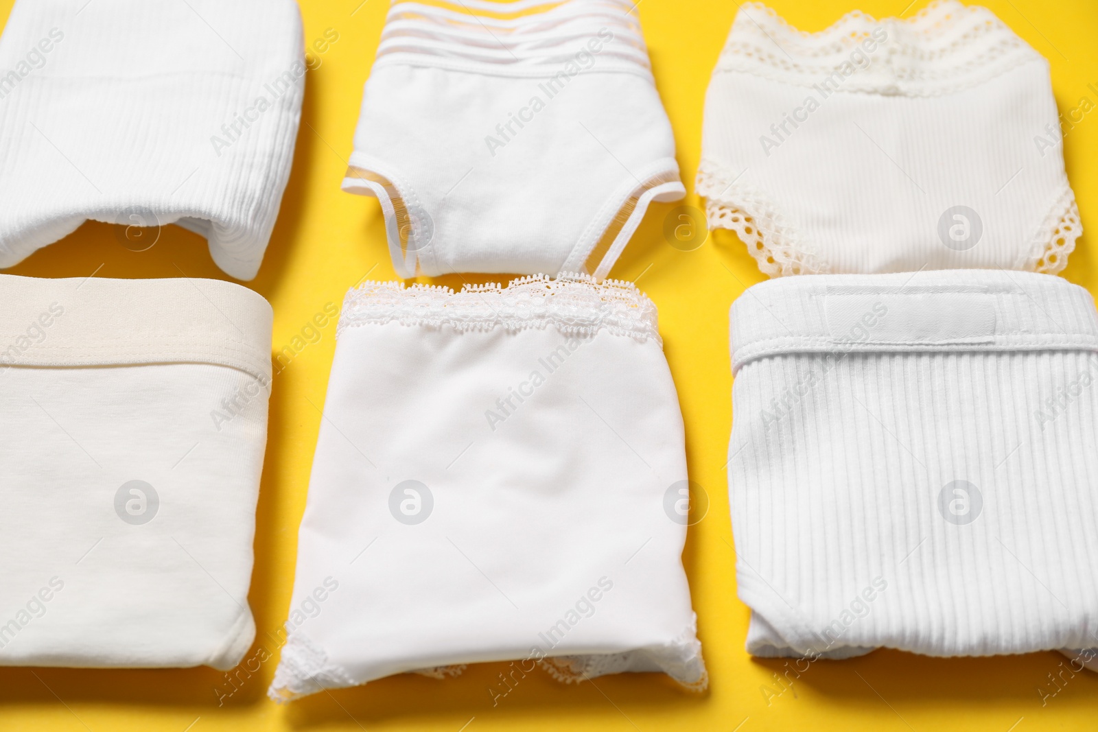 Photo of Stylish folded women's underwear on yellow background