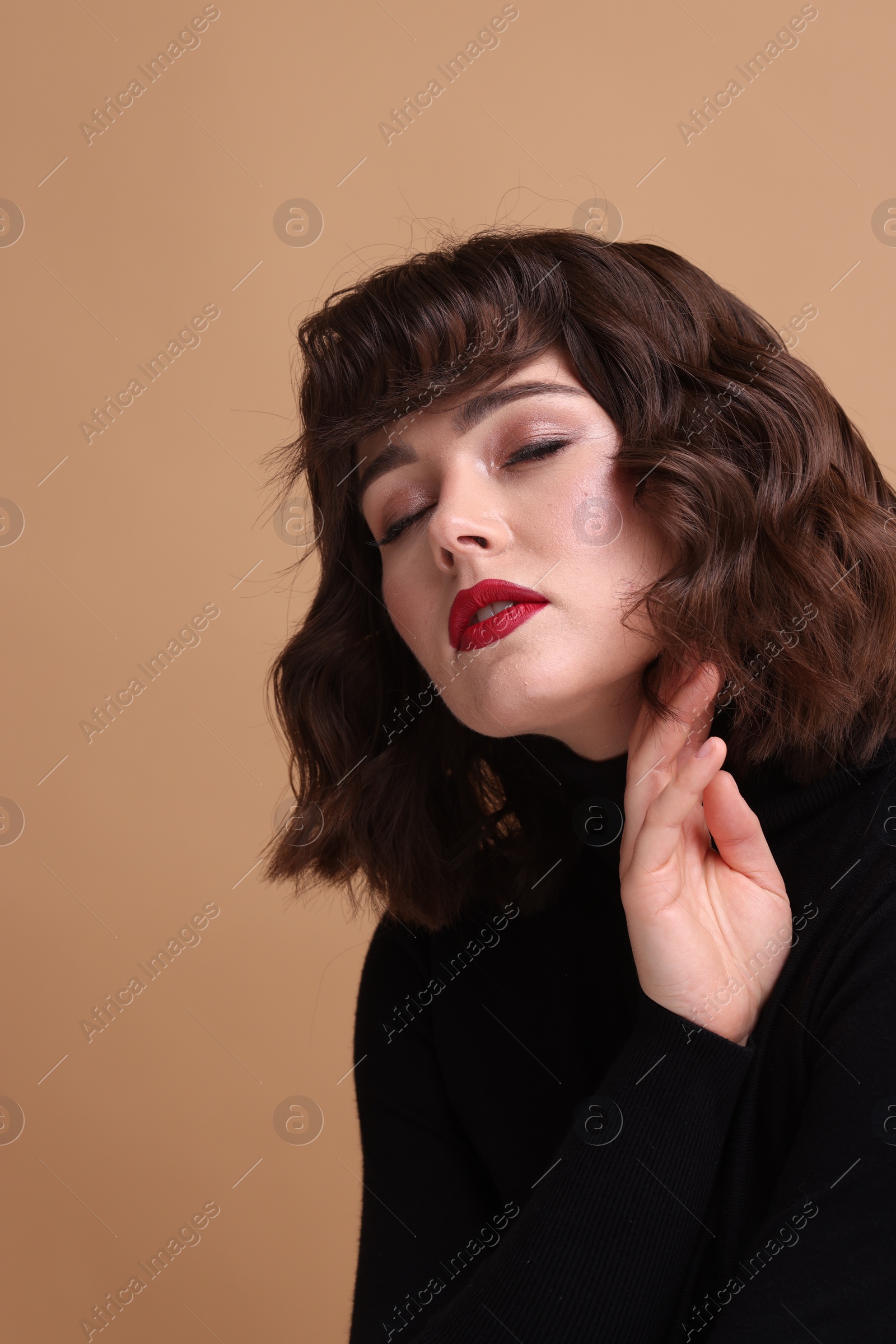 Photo of Portrait of beautiful young woman with wavy hairstyle on beige background