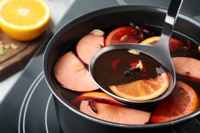 Photo of Delicious hot mulled wine on stove, closeup