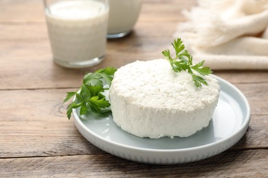 Delicious fresh cottage cheese with parsley on wooden table
