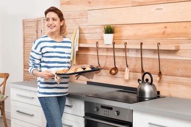 Photo of Young woman with sheet pan of oven baked cookies in kitchen