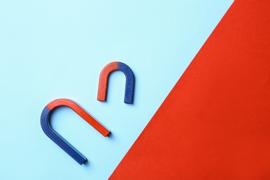 Red and blue horseshoe magnets on color background, flat lay. Space for text