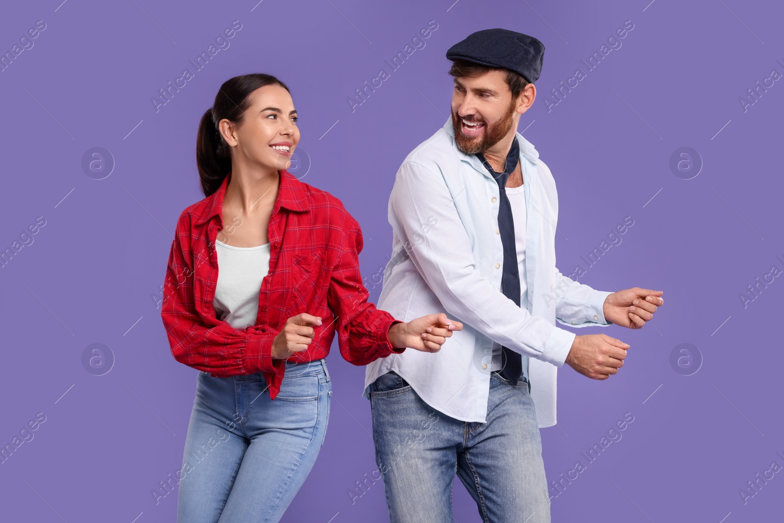 Photo of Happy couple dancing together on violet background