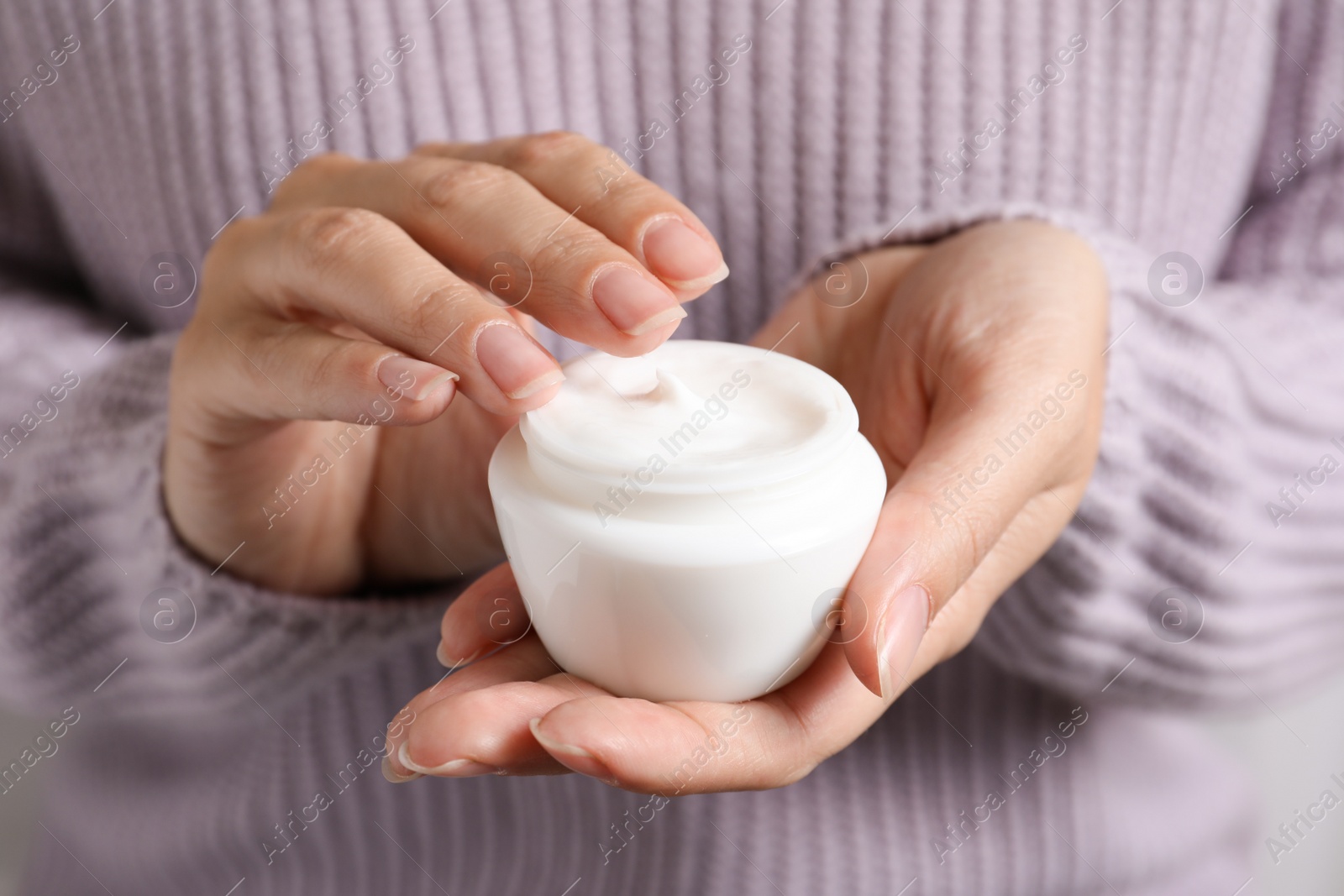 Photo of Woman holding jar of moisturizing cream, closeup. Winter skin care cosmetic