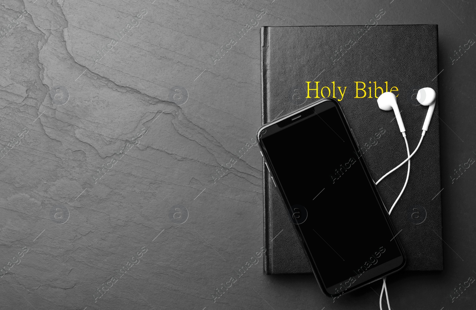 Photo of Bible, phone and earphones on black background, top view with space for text. Religious audiobook