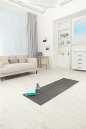 Photo of Exercise mat, yoga block and bottle of water on floor in room