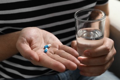 Photo of Man with glass of water and pills, closeup