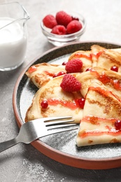 Thin pancakes served with syrup and berries on plate