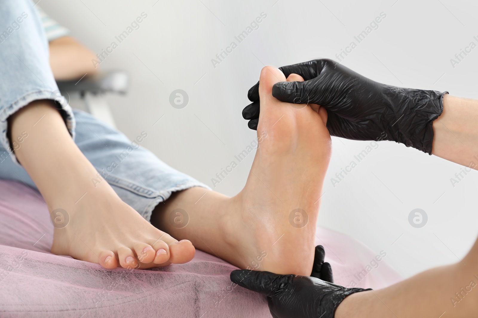 Photo of Professional master making foot massage to client in beauty salon, closeup. Preparation for pedicure procedure