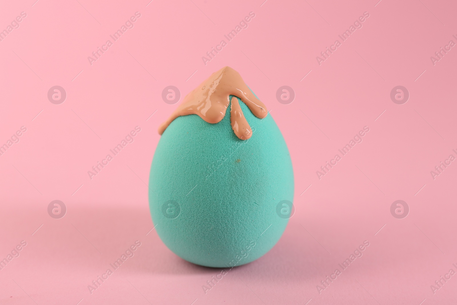Photo of Makeup sponge with skin foundation on pink background, closeup