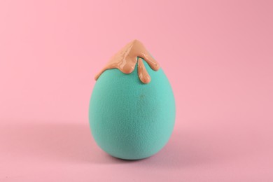 Photo of Makeup sponge with skin foundation on pink background, closeup