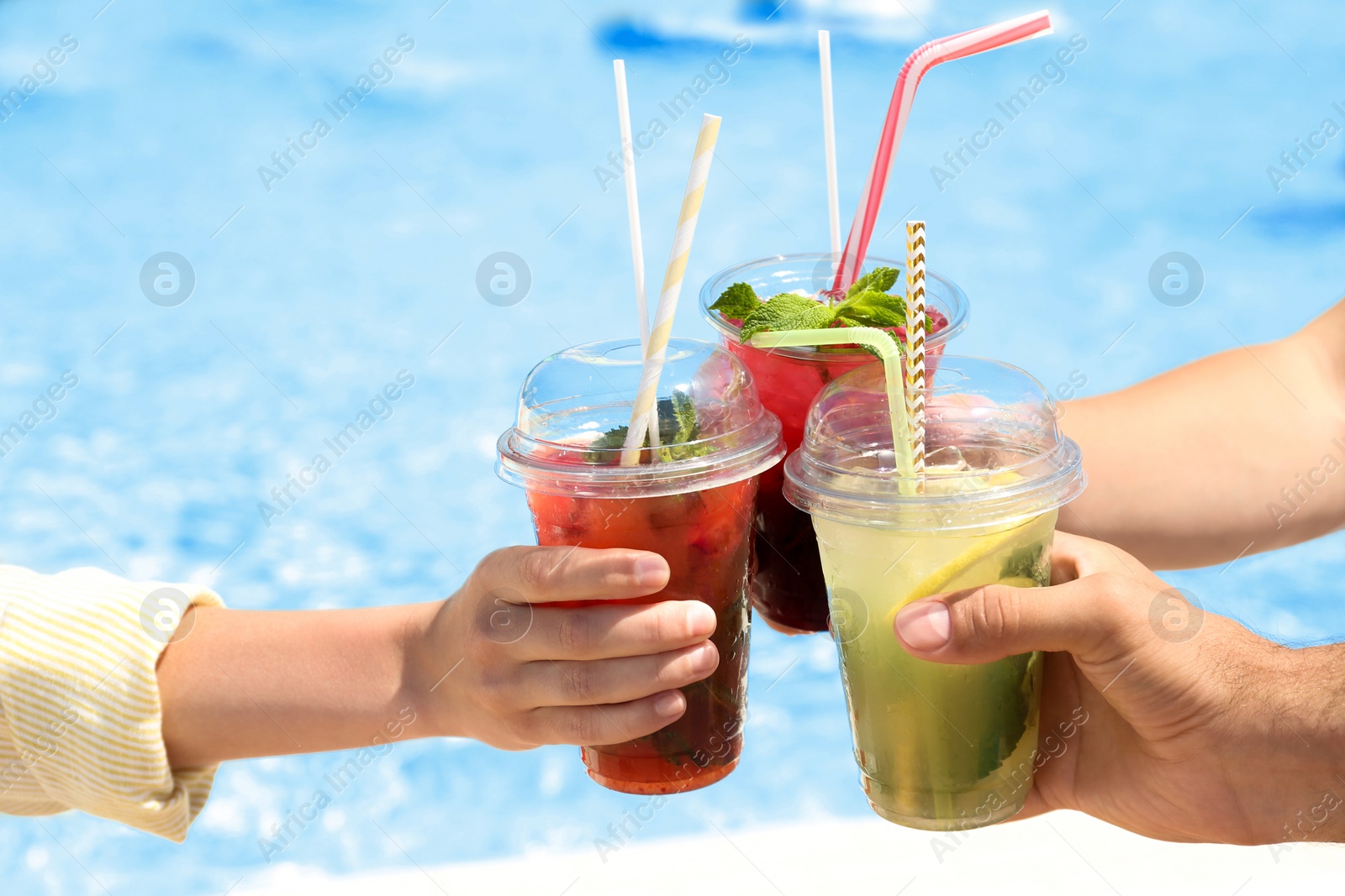 Photo of People with refreshing drinks in water park, closeup