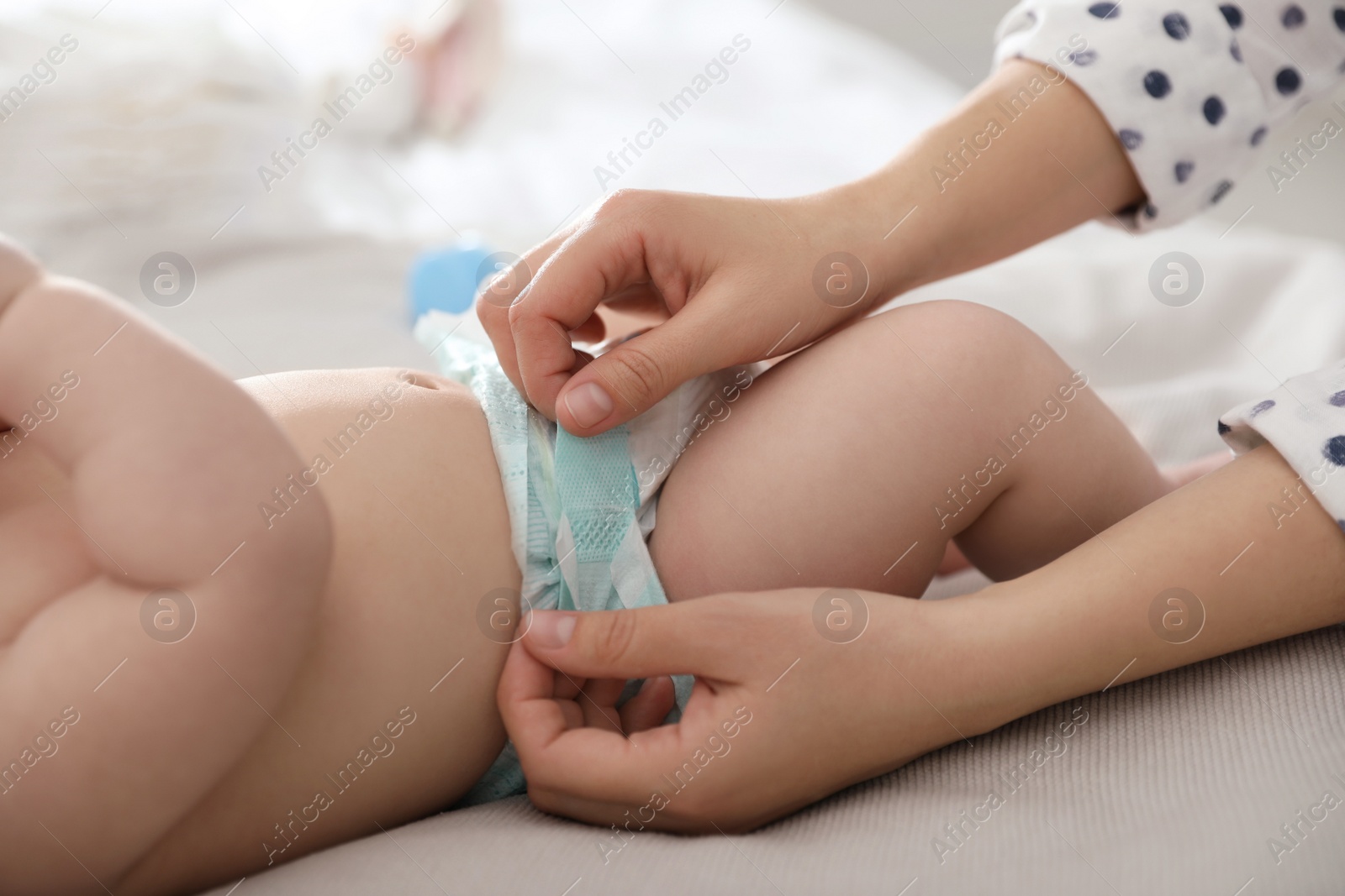 Photo of Mother changing her baby's diaper on bed, closeup