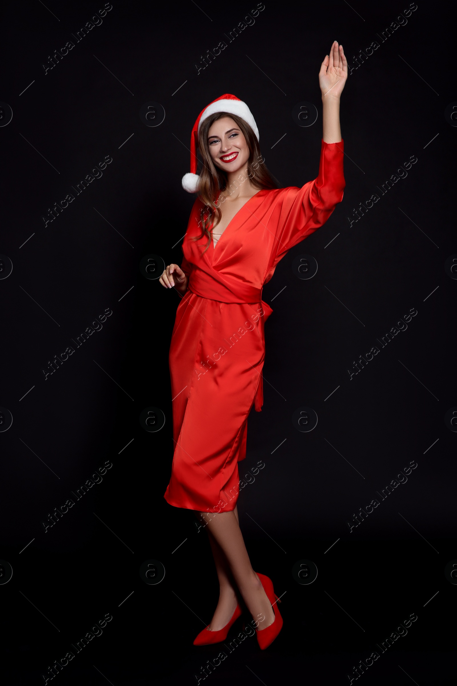 Photo of Happy woman in Santa hat on black background. Christmas party