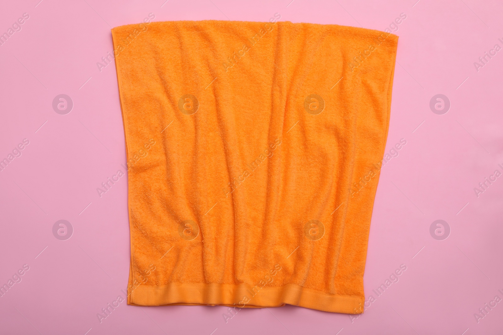 Photo of Crumpled orange beach towel on pink background, top view