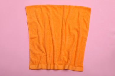 Crumpled orange beach towel on pink background, top view