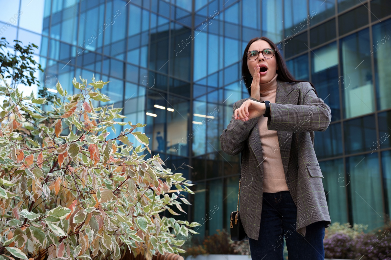 Photo of Emotional woman checking time on watch outdoors. Being late concept