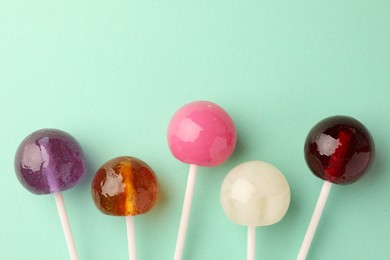 Photo of Tasty lollipops on turquoise background, flat lay. Space for text